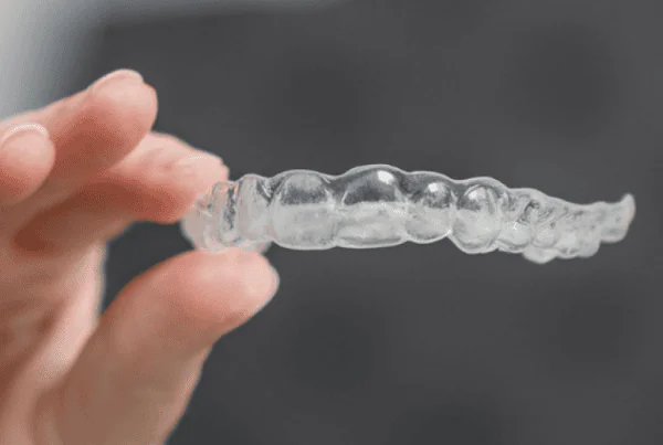 Close-up of a person holding a clear Invisalign aligner for orthodontic teeth straightening.